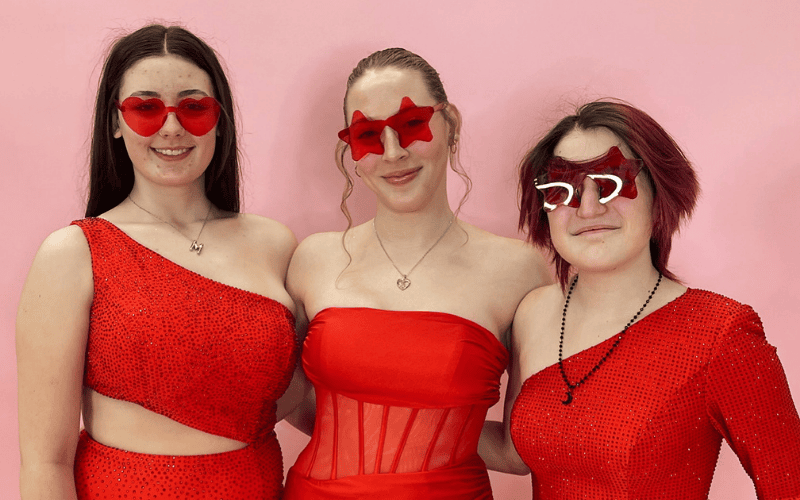 3 girls wearing red prom dresses with a red sunglasses