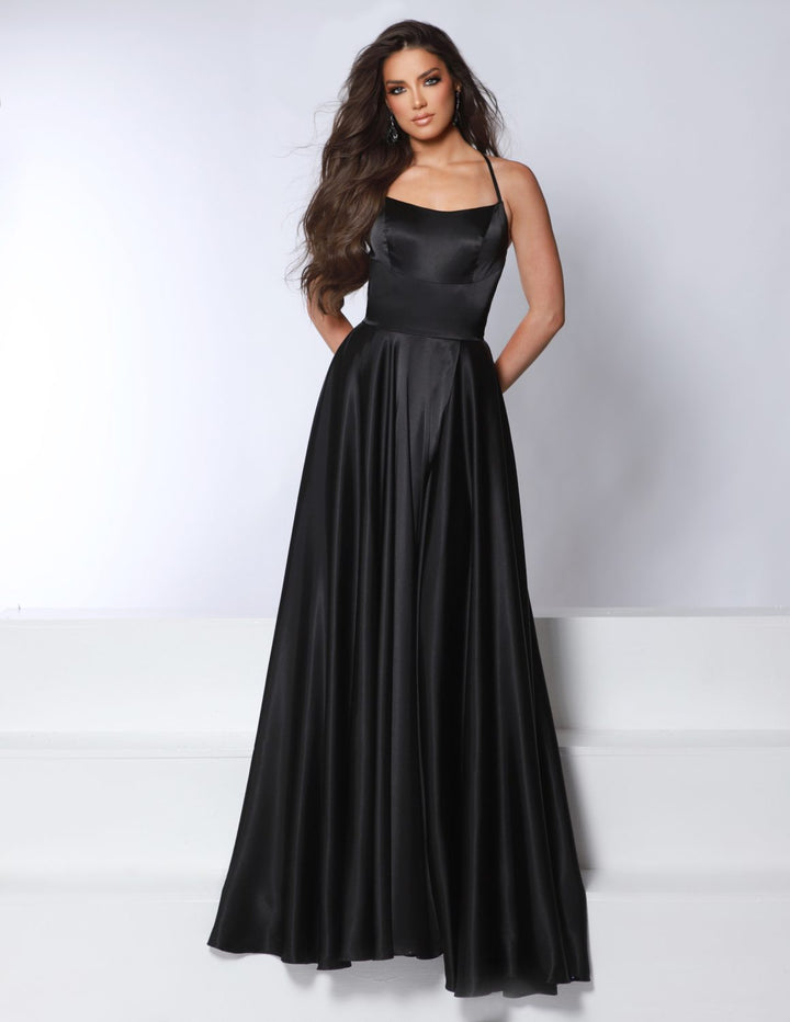 A woman with long, wavy brown hair models the 2Cute 24389, a sleeveless, floor-length black satin gown by 2Cute, standing against a plain white background with her hands in its pockets.