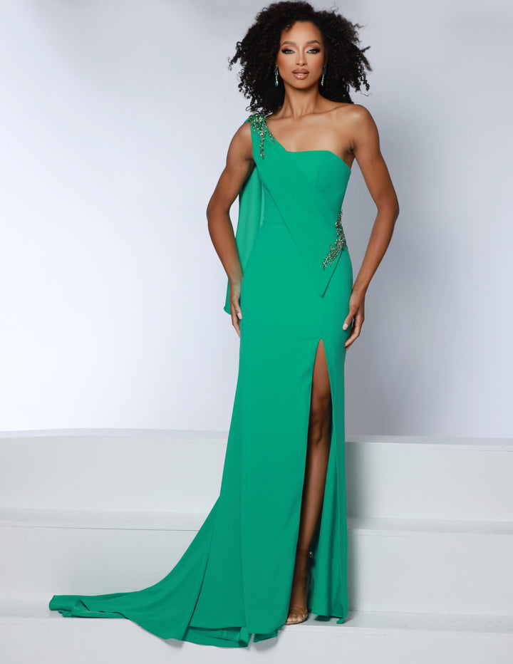 A woman stands confidently on white steps wearing the Johnathan Kayne 2864, a bright green one-shoulder evening gown from Johnathan Kayne featuring a thigh-high slit and decorative embellishments.